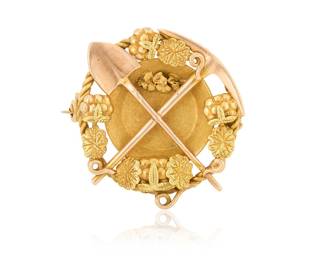 1085 A Bi-Color Gold Brooch Of a miner's motif featuring a gold pan, pick and shovel accented by gold nuggets  Measures: 1 x 1 in. 5.4 grams gross Estimate: $600 - $800