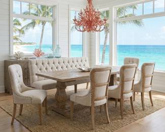 Coastal dining table with a tufted dining bench, upholstered chairs and statement chandelier for a beach-inspired dining room.