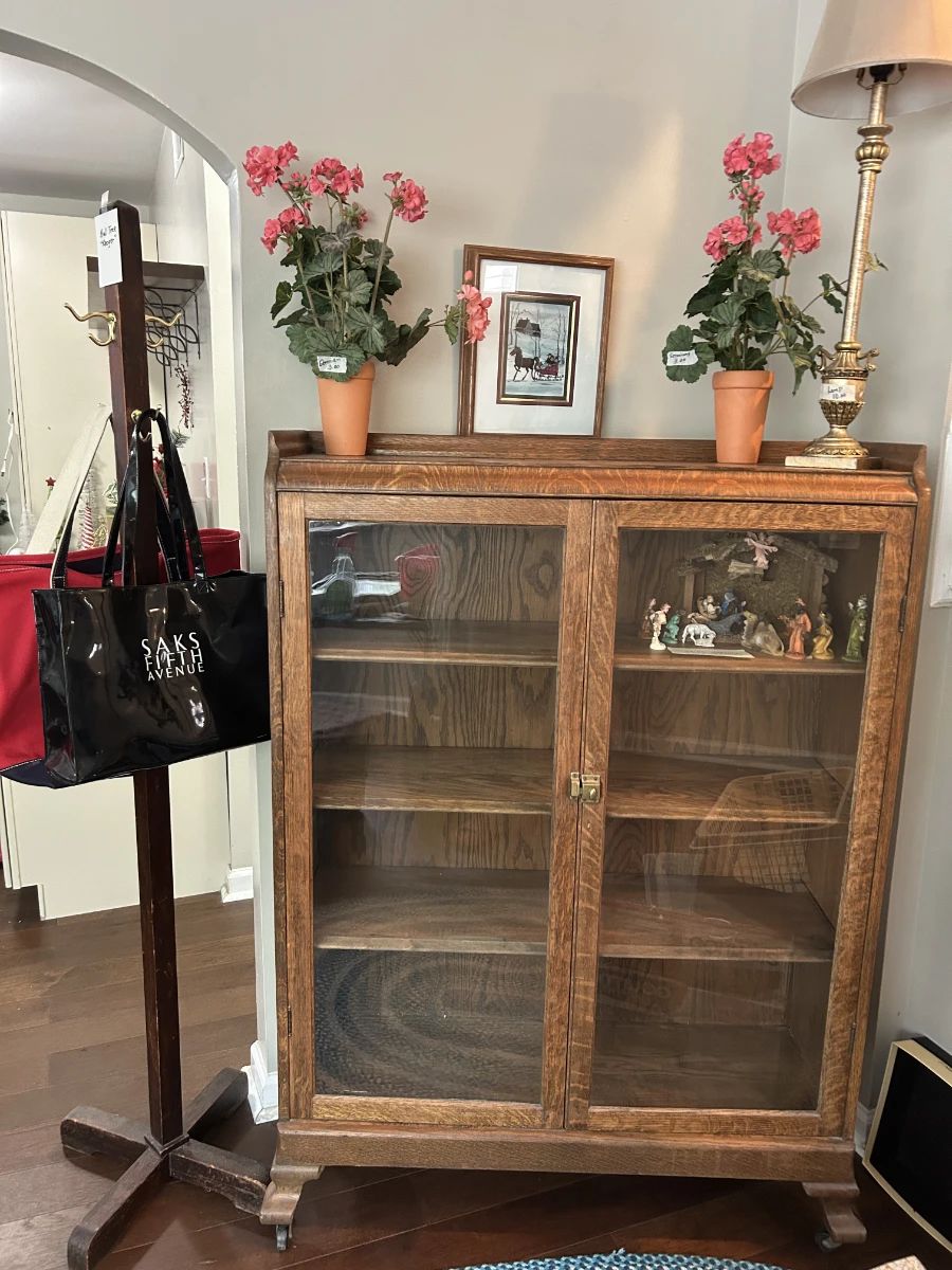 Antique cabinet, vintage clothes tree with a "Kroger" tag on it. Sak vinyl bag, flowers, lamp, nativity set in cabinet