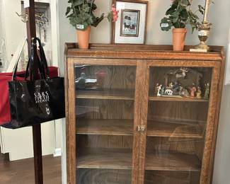 Antique cabinet, vintage clothes tree with a "Kroger" tag on it. Sak vinyl bag, flowers, lamp, nativity set in cabinet