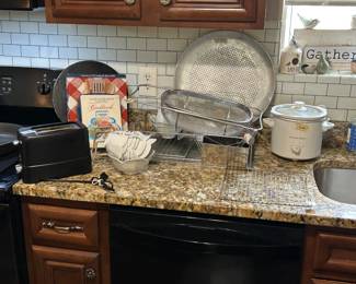 small toaster, cook books, over the sink strainer, small dip crock pot, large pizza pan. Flock of birds on window sill