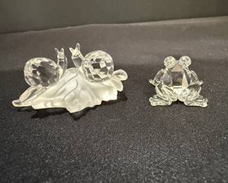 Clear Faceted Glass Snail Pair and Kissing Frogs Figurines Two clear faceted figurines: a pair of snails on a frosted leaf, and a pair of kissing frogs. These sparkling animal figurines catch the light and make a fun addition to a curio shelf or collector's display.