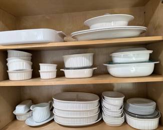 White Fluted Bakeware and Casserole Dish Lot A cabinet of white fluted bakeware, including rectangular baking dishes, oval casseroles with glass lids, ramekins, a divided server, a butter dish, a gravy boat and saucers. Classic white casserole dishes that go from oven to table.