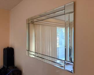 Large Beveled Wall Mirror A large rectangular frameless wall mirror with a border of layered beveled glass panels. A mirror that adds light and sparkle to an entry, dining room or bedroom. The glass looks clear in the photo.