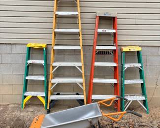Ladder Lot with Two-Wheel Yard Cart Four step ladders, including a tall yellow ladder, an orange ladder and two shorter green ladders, plus a gray and orange two-wheel wheelbarrow-style yard cart. Practical yard and garage equipment. These show normal use wear.