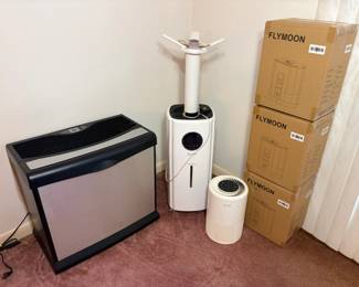 Humidifier and Air Purifier Lot with Flymoon Boxes A home air lot with a large console humidifier, a white tower humidifier, a small round air purifier and three Flymoon humidifiers in their boxes. Working condition not confirmed — sold as found.