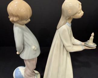 Lladró Porcelain Child Figurines – Boy with Ball and Girl with Candle Two Lladró porcelain child figurines: a boy in a blue jacket with one foot on a ball, and a girl in a long nightgown carrying a candle holder. Soft matte-look colors and sweet poses make this Lladro figurine pair a nice fit for a nursery shelf or display cabinet.