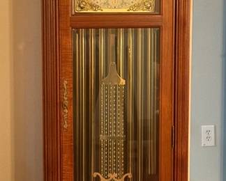 Grandfather Clock with Moon Phase Dial and Brass Pendulum A tall grandfather clock in a warm wood case with a broken-arch top and finial, fluted columns and a glass door showing an ornate brass lyre pendulum, three weights and chime tubes. The brass dial has a moon phase arch. Working condition not confirmed — sold as found.