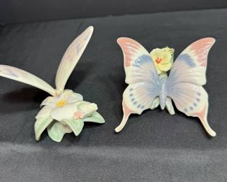Dragonfly on Flower and Butterfly Figurines Two delicate glazed figurines: a dragonfly with long pale wings resting on a white blossom with green leaves, and a pastel butterfly with a yellow flower at its center. A charming pair for a windowsill or garden-themed display.