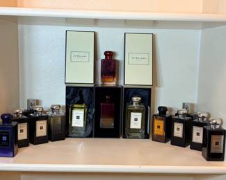 Jo Malone London Fragrance Collection with Boxes A shelf of Jo Malone London fragrances, mostly in dark glass bottles, plus bottles shown in their cream and black Jo Malone boxes. A luxury perfume lot. Fill levels vary — check each bottle in person.