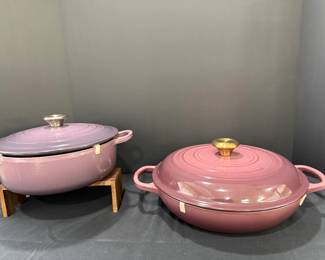 Le Creuset Lilac Casserole and Rose Braiser – Pair Two Le Creuset enameled pieces with embossed lids: a lilac shallow casserole with a stainless knob, and a rose-pink braiser with a gold-tone knob. Pastel Le Creuset cookware for braising and serving. Lid clips are still in place on both.