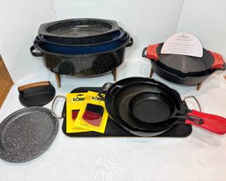 Cast Iron Skillets, Lodge Scrapers and Speckled Enamel Roasters A cookware lot with cast iron skillets with red handle covers, Lodge pan scrapers in their packaging, a cast iron skillet set with a Cuisinel care card, a grill press, two speckled enamel oval roasters and a speckled enamel platter. Great for camp cooking and searing.