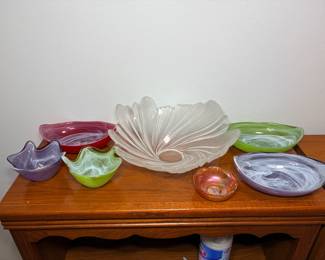 Swirl Art Glass Bowls with Frosted Shell Centerpiece Bowl A lot of colorful swirl art glass bowls in red, green and lavender, a large frosted glass shell-shaped centerpiece bowl and a small iridescent dish. Decorative glass bowls that bring color to a table or sideboard.