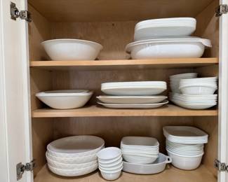 White Dinnerware and Serving Bowl Lot A full cabinet of white dinnerware, including dinner plates, salad plates, soup and cereal bowls, square bowls, ramekins, serving bowls and a lidded casserole. Plain white dishes are easy to mix and match. The pieces look clean and neatly stacked.