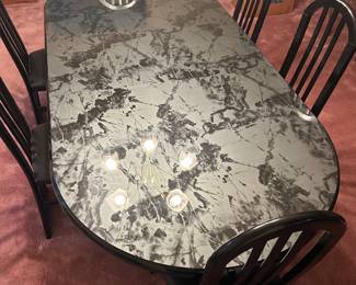 Oval Faux Marble Dining Table with Six Black Chairs An oval dining table with a glossy black and gray marble-look top, surrounded by six black high-back chairs with arched slat backs. A bold contemporary dining set for a dining room or kitchen. The tabletop finish looks glossy in the photo.