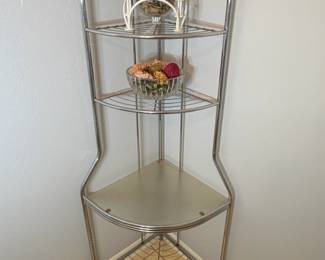 Metal Corner Shelf Étagère A tall brushed metal corner shelf with an arched top, wire shelves and a solid middle shelf. A corner étagère for plants or decor in a bathroom, kitchen or living room. Decor shown may not be included.