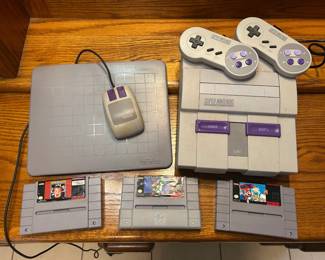Super Nintendo SNES Console with Controllers, Mouse and Games A Super Nintendo Entertainment System console with two controllers, a mouse with a Nintendo mouse pad, and three game cartridges, including Home Alone. A retro video game bundle for SNES collectors. Working condition not confirmed — sold as found.