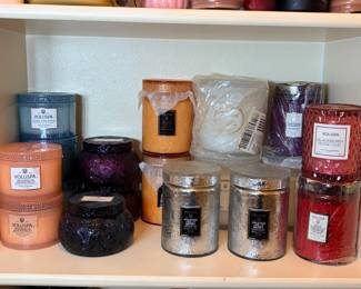 Voluspa Candle Collection A shelf of Voluspa candles in embossed glass and metallic jars and tins, including Casa Pacifica, Magnolia Grapefruit, Frosted Holly Berry, Blackberry Rose Oud and Santiago Huckleberry. Some are still wrapped. Luxury home fragrance that makes a great gift.