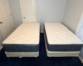 Pair of Twin Pillow-Top Mattresses with Box Springs Two twin-size pillow-top mattresses with box springs on bed frames, set up side by side. A ready-made twin bed set for a guest room or kids' room. The mattresses look clean in the photo.