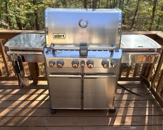 Weber Summit Stainless Gas Grill A Weber Summit gas grill with a stainless hood, hood thermometer, multiple control knobs, two side shelves and a two-door cabinet base, with grill tools hanging on the side. A large backyard grill for serious outdoor cooking. Working condition not confirmed — sold as found.