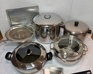 Stainless Cookware Lot – Stockpot, Steamer, Sauté Pan and Pizza Pan A lot of stainless cookware, including a large lidded stockpot, a saucepot, a two-tier steamer pot, a glass-lid sauté pan, a mesh colander, a pizza pan and a serving spatula. A solid pot and pan lot for a busy kitchen.