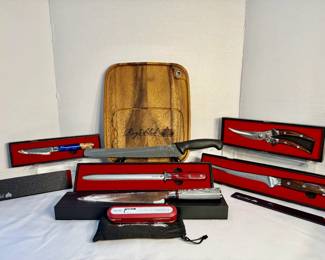 Ray's Club Knife and Kitchen Gift Set with Wood Cutting Board A Ray's Club kitchen collection with an engraved wood cutting board, a bread knife, a paring knife with a blue handle, a honing steel, a fillet knife, poultry shears, a chef's knife and a Ray's Club thermocouple thermometer, most in branded presentation boxes. A gift-ready knife set for a home cook or griller.