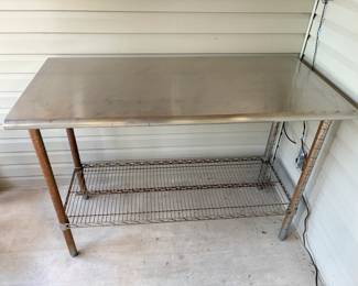 Stainless Top Work Table with Wire Shelf A stainless-look metal top work table with a lower wire storage shelf. A utility prep table for a kitchen, garage, potting area or workshop. The legs show some surface rust.