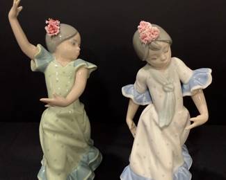 Lladró Porcelain Flamenco Dancer Figurines – Pair Two Lladró porcelain figurines of girls caught mid-dance in ruffled flamenco dresses, one in soft green and one in blue and white, each with sculpted pink porcelain flowers in her hair. The graceful poses make this Lladro dancer pair a lovely centerpiece for a curio cabinet.
