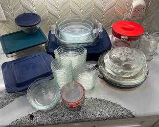 Pyrex Glass Storage and Bakeware Lot A Pyrex lot with glass storage containers and lids, a baking dish with a zippered carry cover, nesting glass bowls, custard cups, pie plates and a Pyrex measuring cup with a red lid. Dependable glass kitchenware for baking and leftovers.