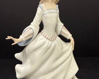Lladró Porcelain Lady in Flowing Gown Figurine A Lladró porcelain figurine of a young woman in a long flowing gown with flared sleeves and a beaded headband, set on an oval base. The soft white and pastel glaze and sense of movement give this Lladro lady figurine an elegant look for a curio or mantel.
