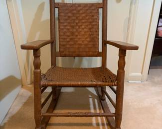 H29 - $40. Wood rocking chair with woven seat and back. Measures 26.25" x 24" x 35"T. Some separation of seat weaving as shown in photo.