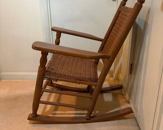 H29 - $40. Wood rocking chair with woven seat and back. Measures 26.25" x 24" x 35"T. Some separation of seat weaving as shown in photo.