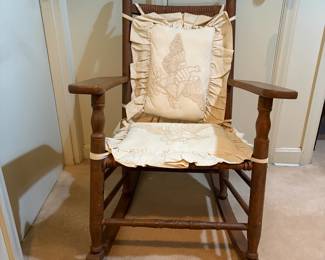 H29 - $40. Wood rocking chair with woven seat and back. Measures 26.25" x 24" x 35"T. Some separation of seat weaving as shown in photo.