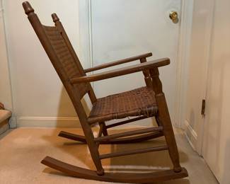 H29 - $40. Wood rocking chair with woven seat and back. Measures 26.25" x 24" x 35"T. Some separation of seat weaving as shown in photo.