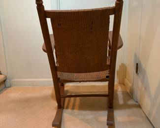 H29 - $40. Wood rocking chair with woven seat and back. Measures 26.25" x 24" x 35"T. Some separation of seat weaving as shown in photo.