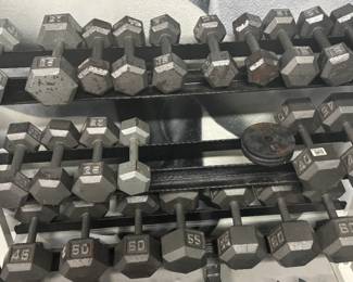 Commercial 3-Tier Rack & Heavy Dumbbell Run (40–60 lbs) With white-framed, 3-tier rack shown commercial-grade, white-framed 3-tier steel rack holds a robust run of solid cast-iron hex dumbbells, scaling through the demanding 40 lb, 45 lb, 50 lb, 55 lb, and 60 lb pairs. The package is augmented with a curated set of vintage iron Olympic change plates sitting on the middle tier, perfect for precision progression.