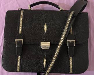 Ultra-Exclusive Genuine Pearl Stingray Skin Executive Briefcase Uncompromising executive distinction. This magnificent, museum-quality briefcase is crafted from genuine black stingray skin, celebrated globally for its diamond-hard durability and unique, light-catching mineral texture. The face is masterfully centered around two striking white "pearl" dorsal spine marks, beautifully framed by racing stripes of matching polished stingray skin. Outfitted with heavy brushed-steel hardware, a secure central lock, and an exceptional full-length matching stingray leather shoulder strap, this asset commands attention in any boardroom. A rare, high-end investment piece for the true collector.