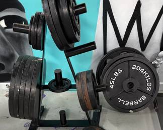 Heavy-Duty Olympic Plate Tree with Cast Iron Weight Plates (~350–400 lbs total)  robust, multi-tier A-frame Olympic plate tree fully loaded with standard 2-inch Olympic cast iron weight plates. Includes premium brands like CAP Barbell (the "20.4 KILOS / 45 LBS" plate clearly showcased on the right) and Ivanko / Barbell styles on the tree. The plates are mostly standard black-painted cast iron