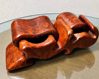 Decorative Carved Wood Sculpture — Rich reddish-brown burlwood-style finish with swirling grain patterns, smooth polished surfaces, and an abstract interlocking design.