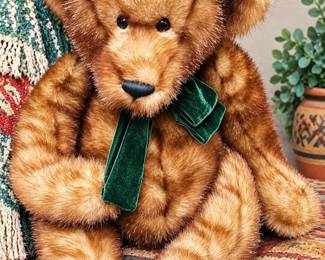 Large plush teddy bear with soft golden-brown faux fur, oversized paws, and forest-green velvet bow.