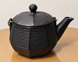 Black Cast-Iron Teapot — Japanese-style textured geometric design with ribbed detailing, fitted lid, and curved pouring spout.