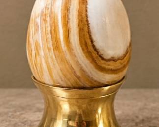 Striped Stone Egg — Polished cream and caramel-colored stone with distinctive concentric banding and brass stand.