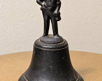 Vintage Cast-Iron Figurine Bell — Black metal bell topped with a standing gentleman figure, featuring a textured finish and traditional flared base.
