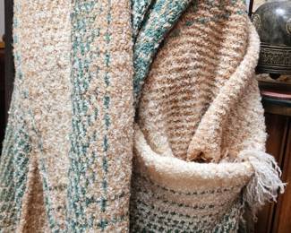 Cozy, textured cream and sage-green woven throw blanket with decorative pattern and fringed edges.
