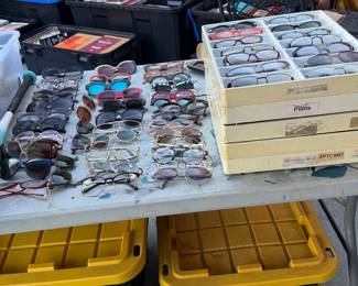 assortment of vintage and contemporary eyeglasses, sunglasses, optical frames, aviators, oversized statement glasses, colorful retro frames, and unique designer-style eyewear. Featuring an eclectic variety of shapes, colors, materials, and styles from different decades, including metal, acetate, tortoiseshell-style, and bold fashion frames.