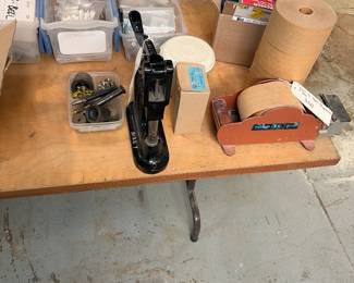 Stimpson 405 Gromit and eyelet press, packer tape dispenser with four rolls, adhesive transfer tape, and hardware.