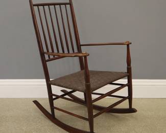 A late 19th to early 20th century Shaker style rocking chair.  Features a rod back and tape seat.  Wear and minor scratches to original finish, replaced seat, some minor touchups.  37 1/2" high.  