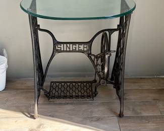 A decorative side table made from an antique Singer treadle sewing machine cast-iron base