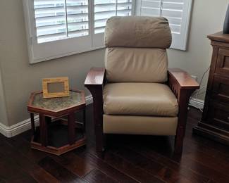 Mission-style beige leather recliner with wide wooden armrests, positioned next to a vintage hexagonal accent table