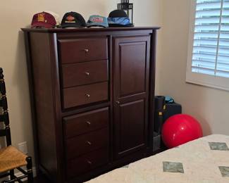 Dark espresso wooden armoire dresser featuring six stacked drawers, a tall cabinet door, and baseball caps displayed on top.